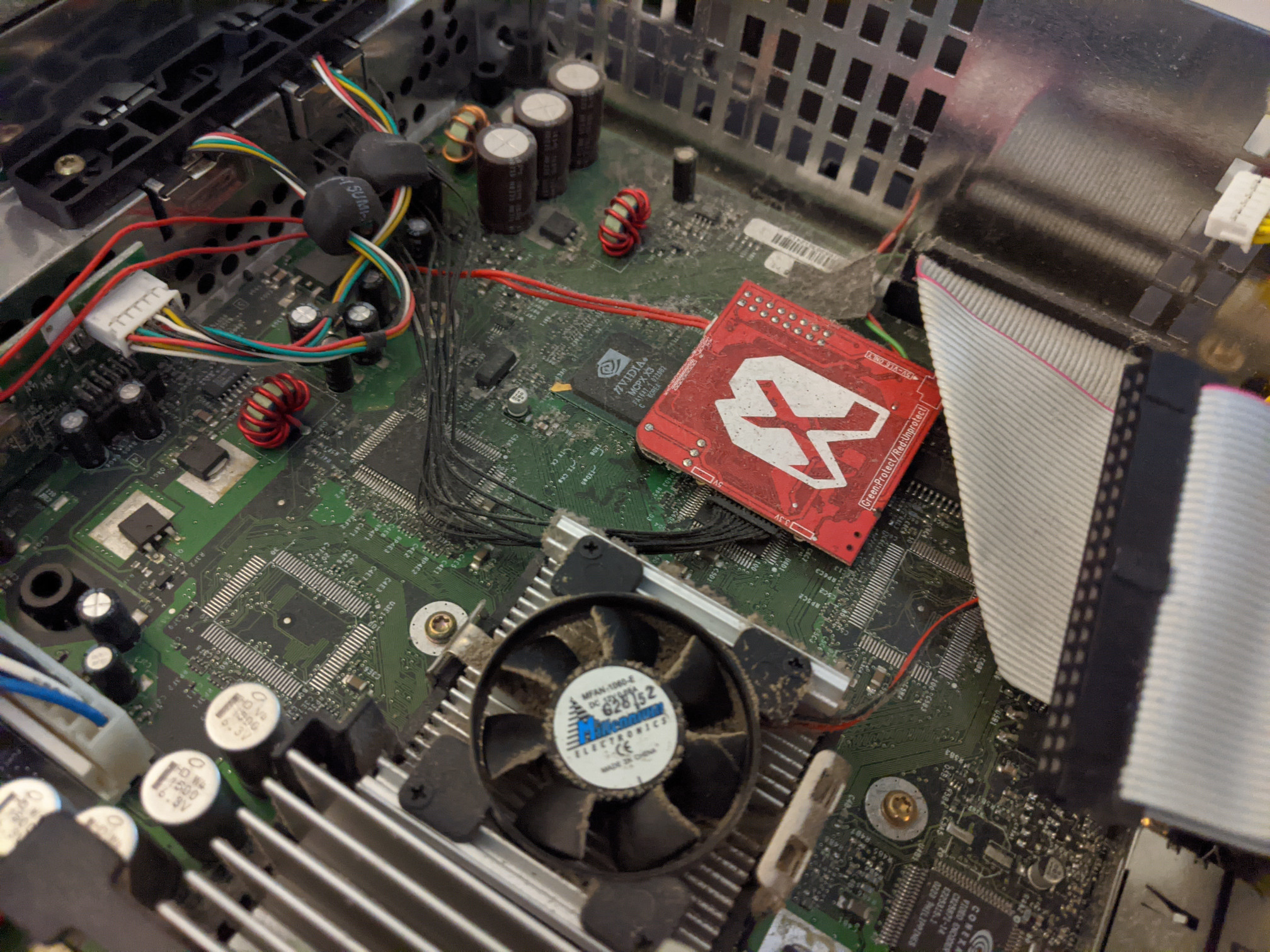 Picture of an old, dusty inside of an Xbox with an Xecuter 3 mod chip installed